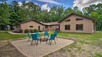 A two-story house with a patio area featuring four blue chairs and a small table.