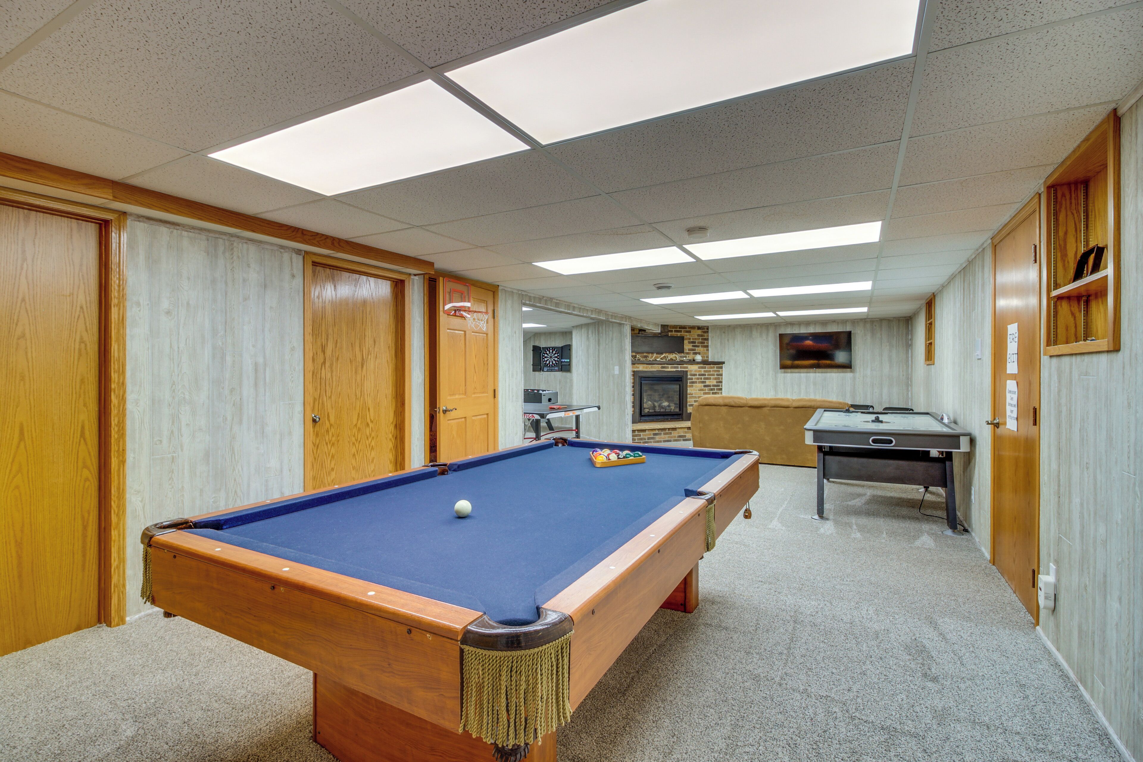 A pool table in a room with wooden walls and a carpeted floor.