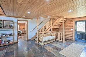 A wooden interior with a staircase, a bench, and a door with a window.