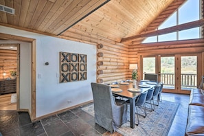 A wooden interior with a dining area, large windows, and a view of the outdoors.