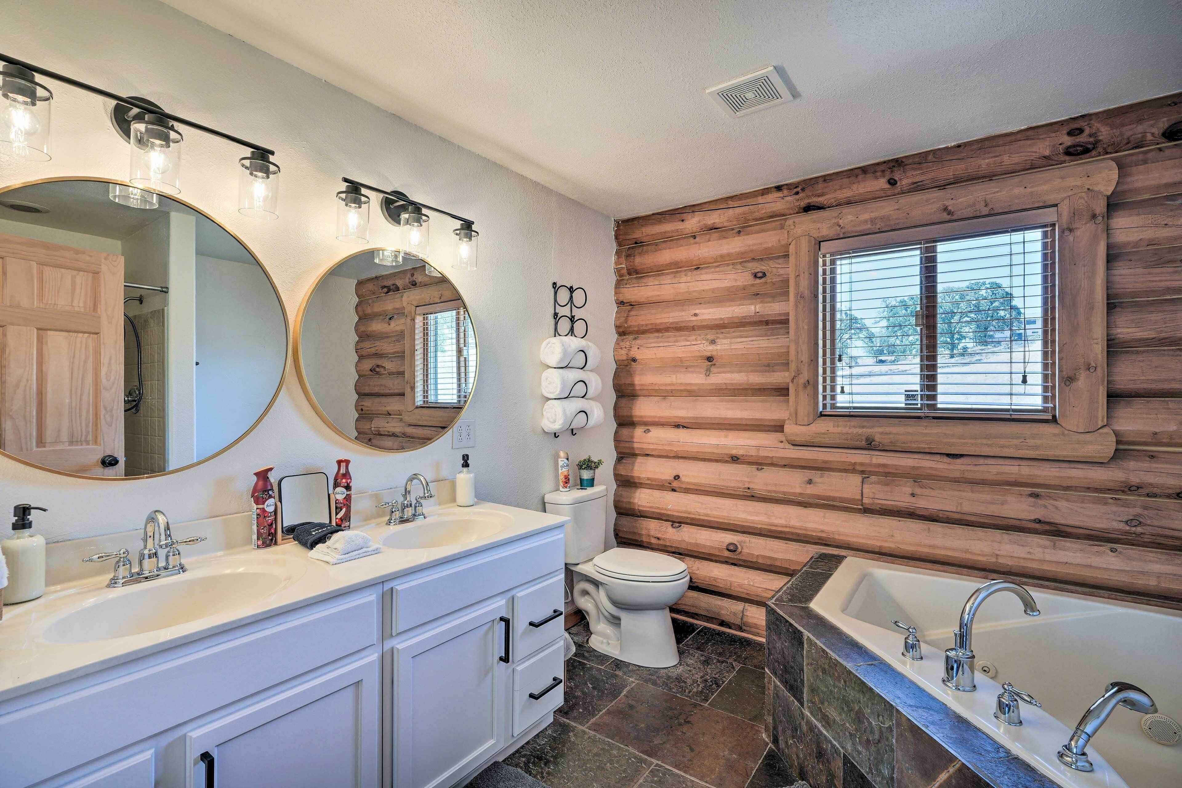 Une salle de bain avec un mur en bois, un grand miroir, un lavabo, des toilettes et une baignoire.