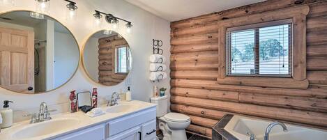 Une salle de bain avec un mur en bois, un grand miroir, un lavabo, des toilettes et une baignoire.