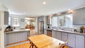 A spacious kitchen with a wooden dining table, grey cabinets, and a large window. - Quaint Woodstock Escape - 2 Mi to Tinker St! (West Hurley)