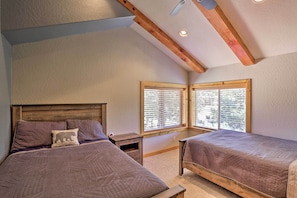 Ein Schlafzimmer mit zwei Betten, Holz-Kopfteilen, einem Nachttisch und einem Fenster mit Jalousien.