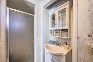 Une salle de bain avec un lavabo blanc, un miroir et un meuble placé au-dessus.