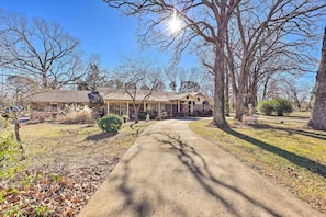 A residential property with a paved driveway leading to a house with a covered porch and a garage.