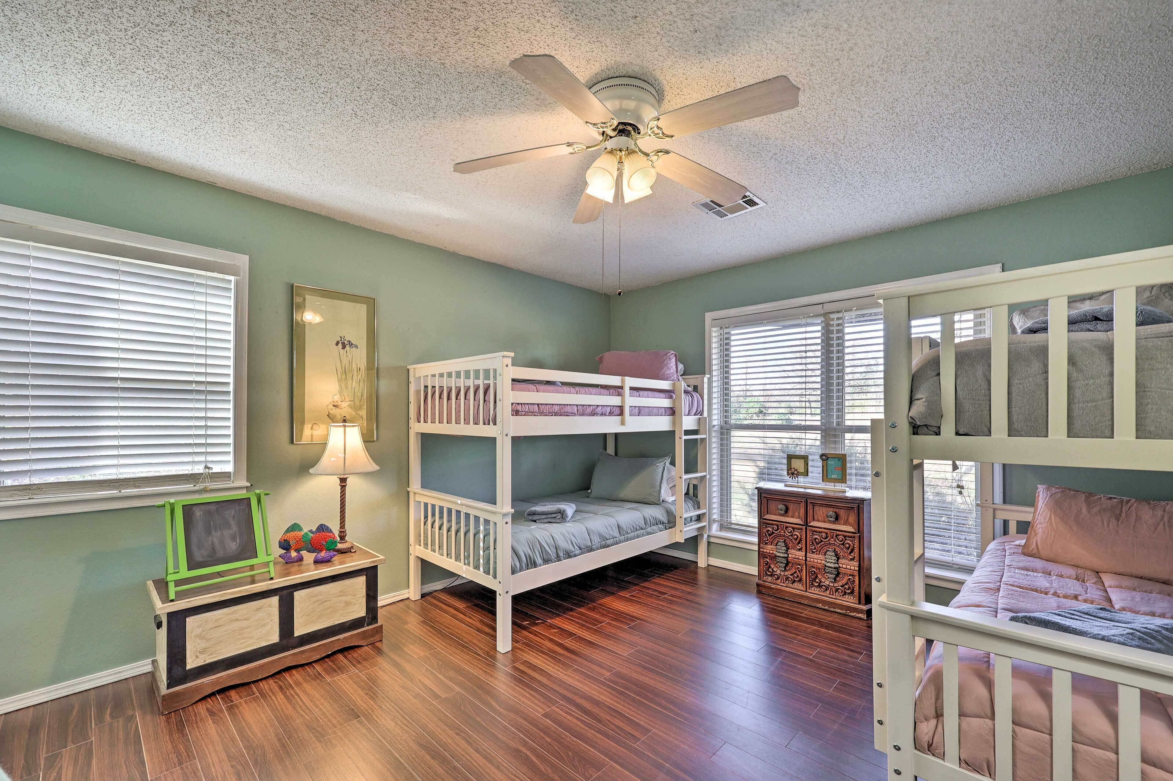Una habitación infantil con literas, ventilador de techo y cómoda.