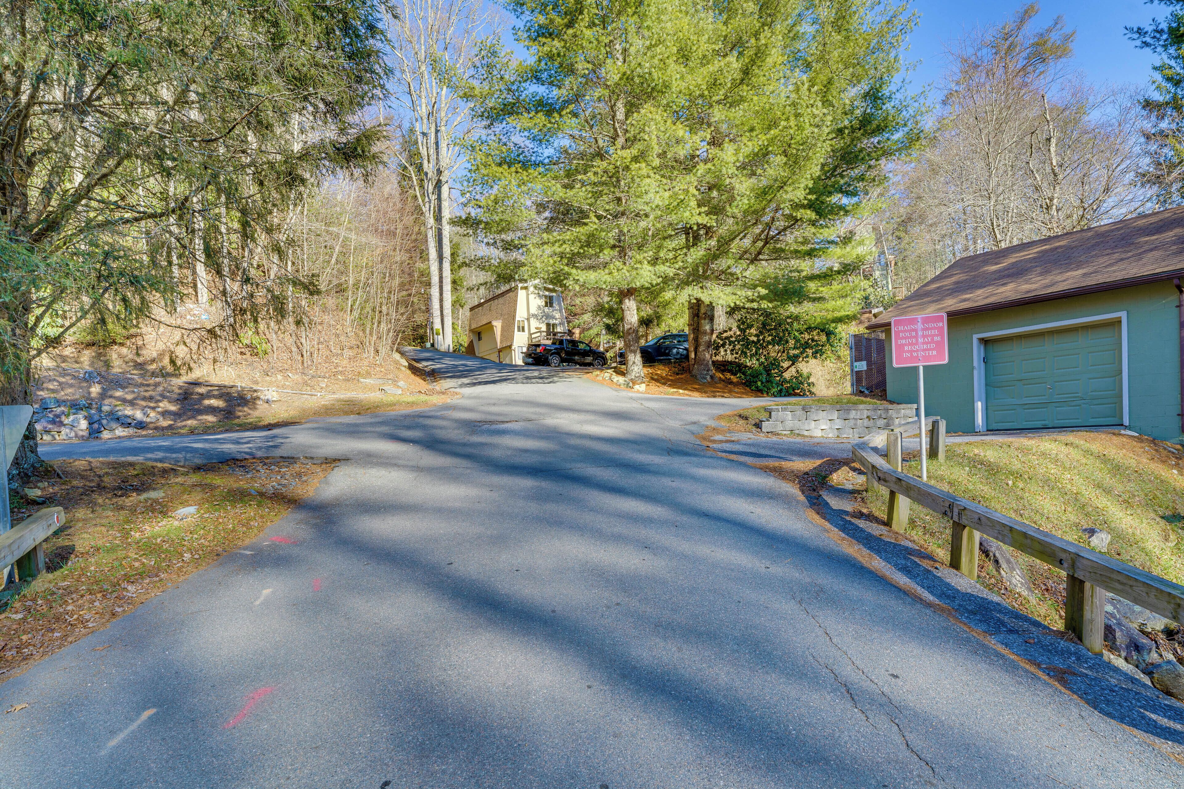 A residential driveway leading to a garage with a wooden fence and a sign.
