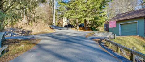 A residential driveway leading to a garage with a wooden fence and a sign.