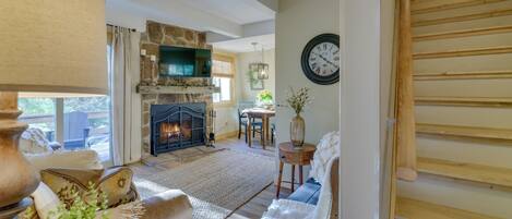Una sala de estar acogedora con chimenea, asientos cómodos y una escalera que sube.