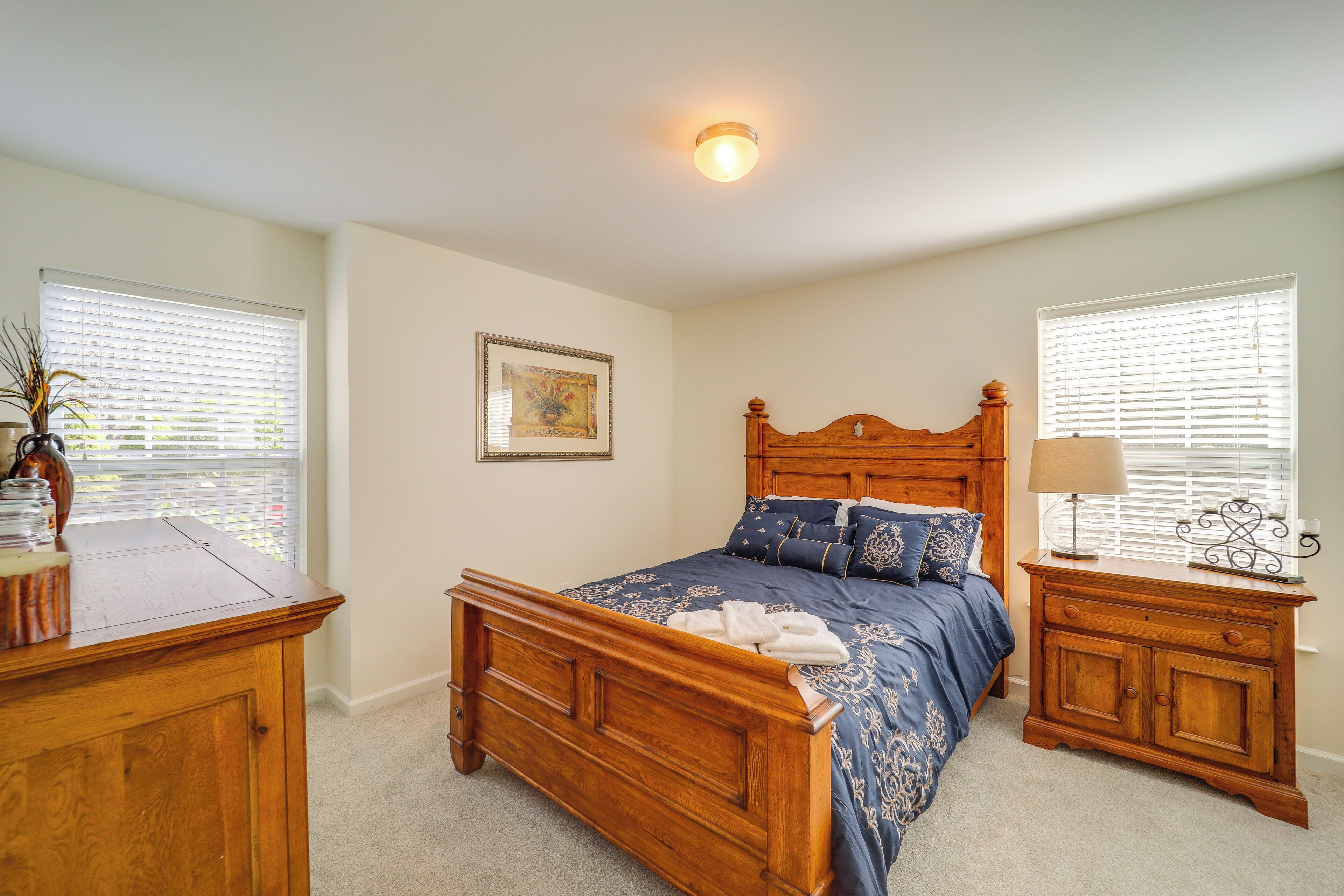 A bedroom with a wooden bed, a nightstand, a lamp, and a picture on the wall.