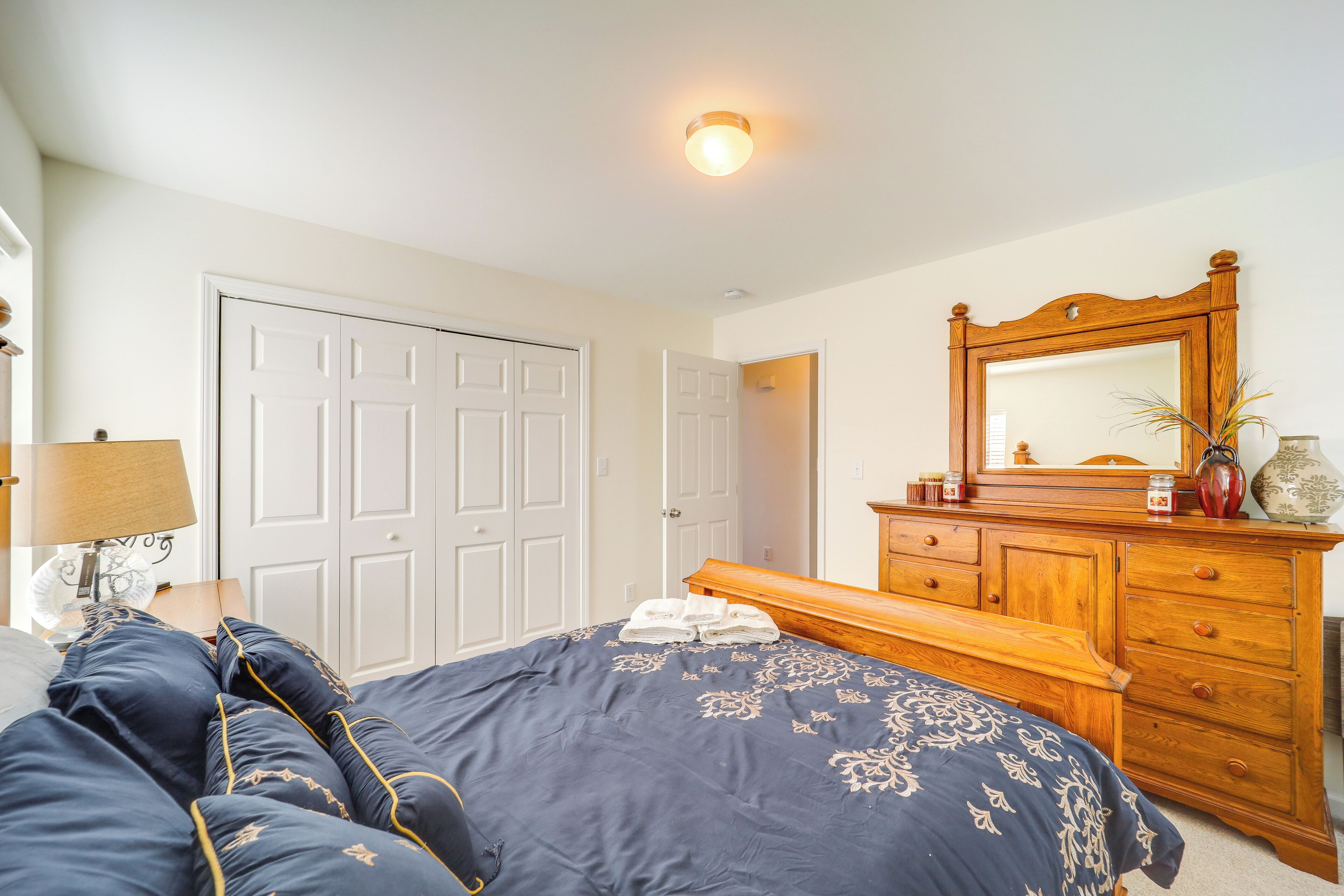 A bedroom with a bed, dresser, mirror, and a door.