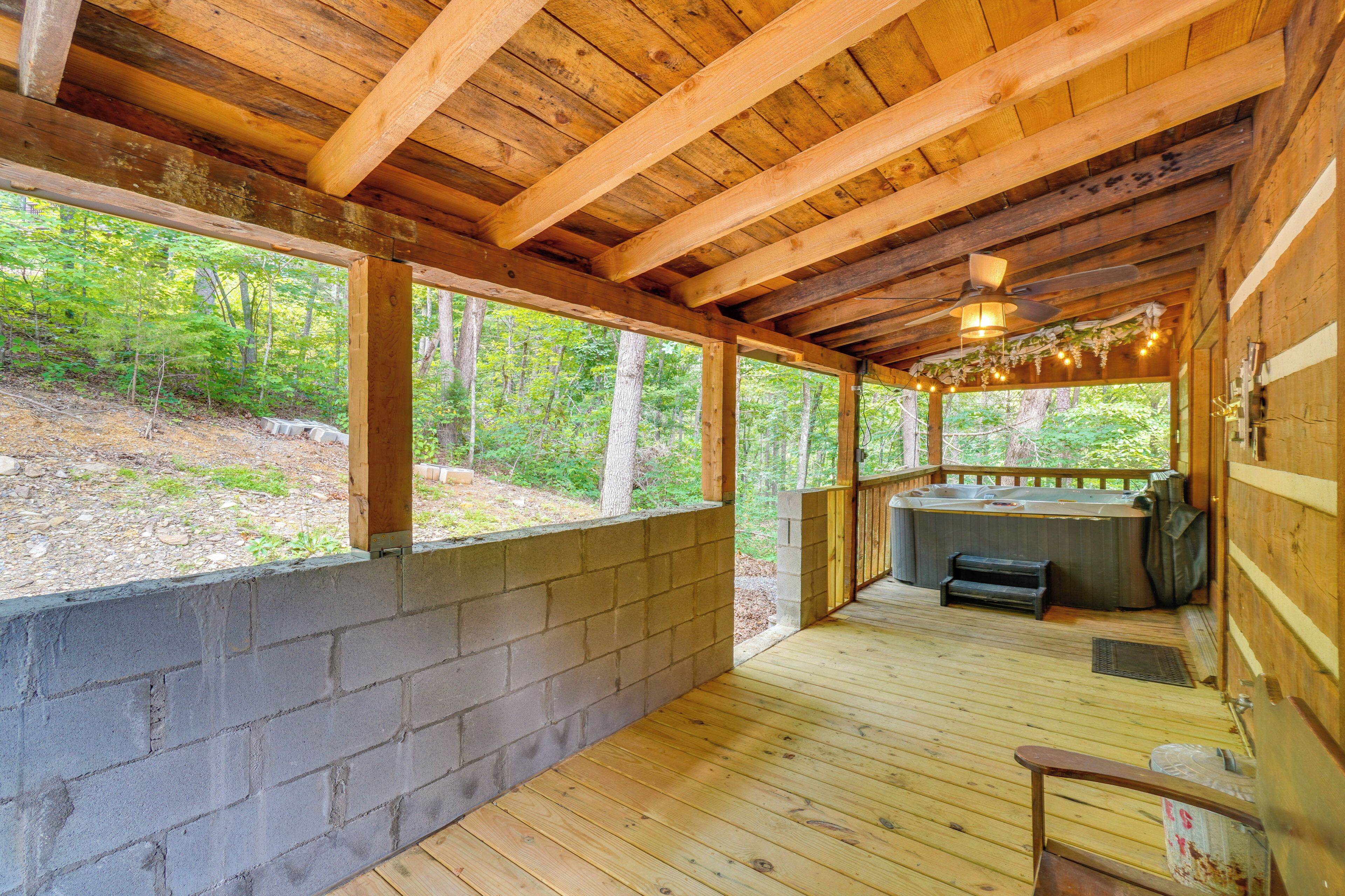 Una cabaña de madera con jacuzzi, terraza y vistas al bosque.
