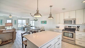 A spacious kitchen with white cabinetry, a large island, stainless steel appliances, and pendant lighting.