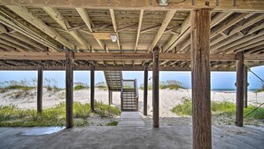 A wooden pier structure with a concrete walkway leading to a bench and a staircase.
