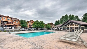 A swimming pool with lounge chairs, surrounded by buildings and trees.
