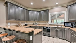 A kitchen with grey cabinets, a granite countertop, a built-in oven, and a microwave.
