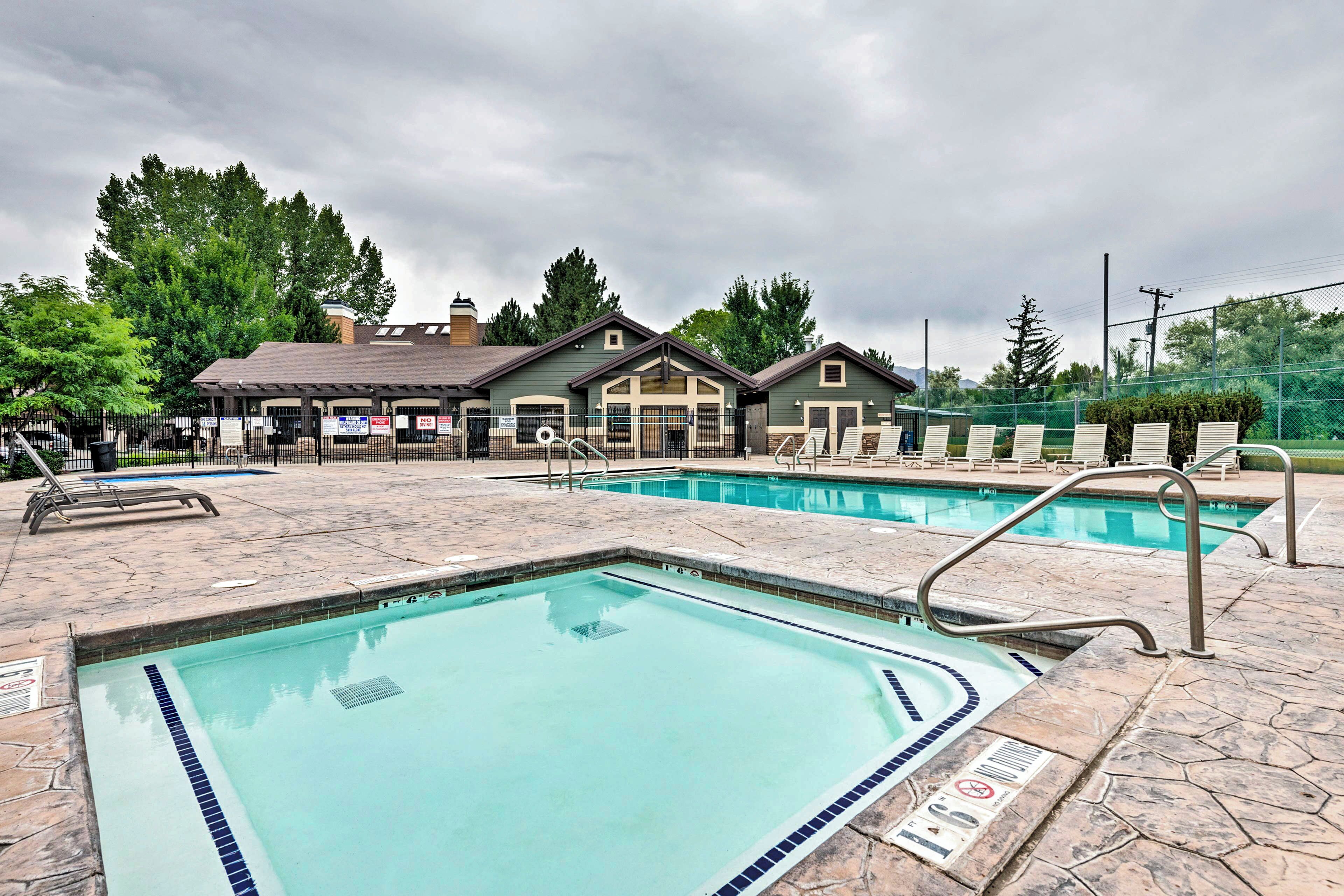 A swimming pool area with a stone deck, lounge chairs, and a building with a green roof.