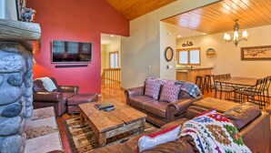 A spacious living room with leather sofas, a wooden coffee table, and a stone wall. - Steamboat Springs Townhome: 1 Block to Ski Lifts! (Steamboat Springs)