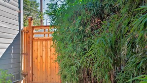 A wooden gate with a metal latch, surrounded by dense bamboo foliage. - Warm & Inviting Ashland Cottage < Half-mile to SOU (Ashland)