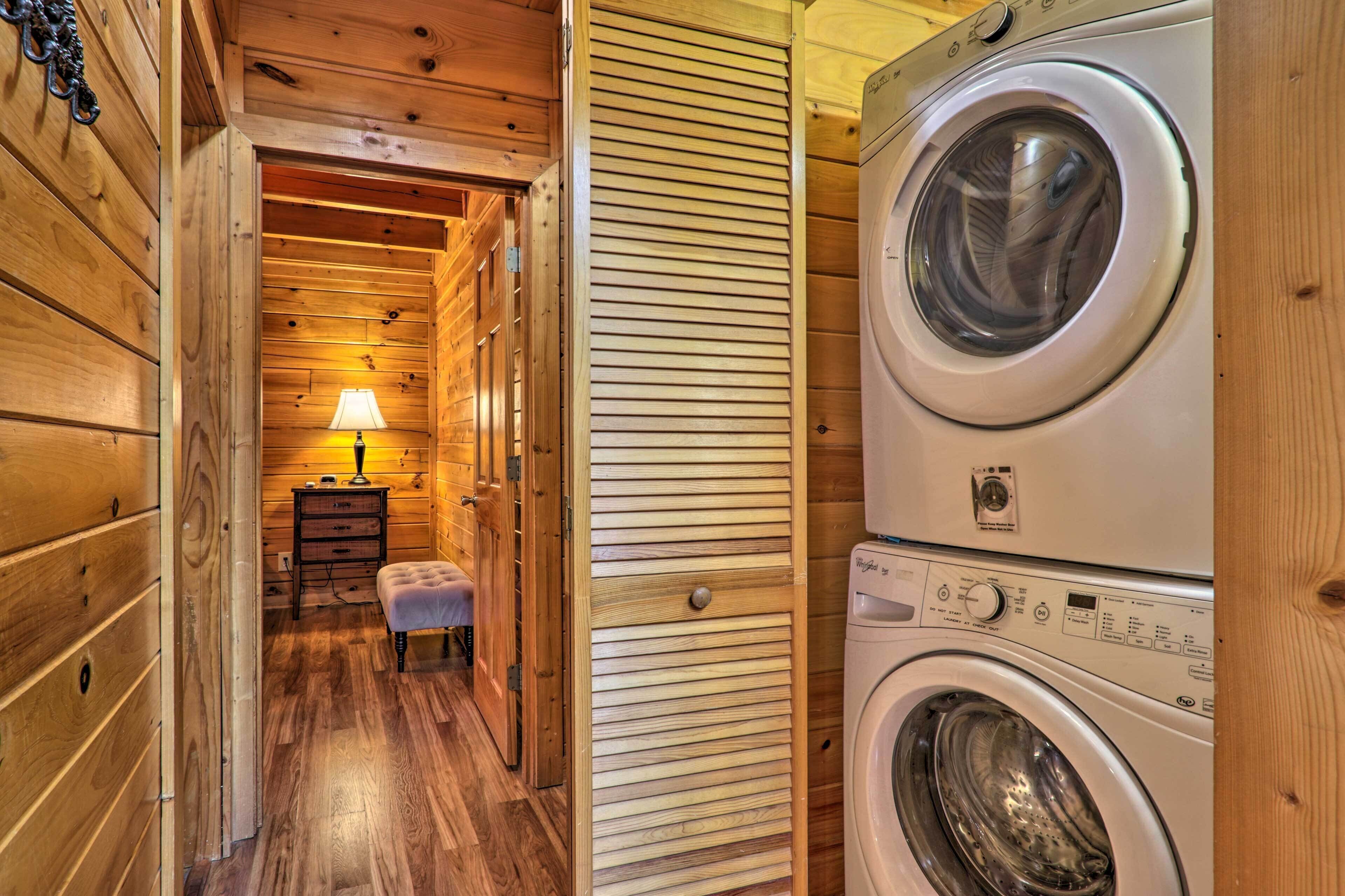 A laundry room with wooden walls and a washing machine.