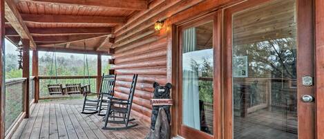 A wooden cabin with a porch, rocking chairs, and a welcome sign.