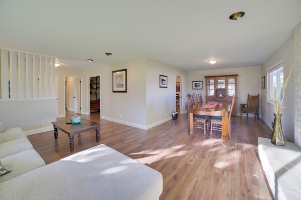A spacious living room with hardwood flooring, a large sofa, a dining area with wooden furniture, and a view of the outdoors through a window. - Quiet Salinas Vacation Rental 10 Mi to Beach (Salinas)