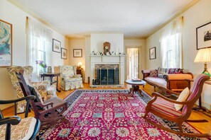 A traditional living room with a fireplace, floral-patterned chairs, a patterned rug, and a sofa with striped cushions. - Terre Haute Manor Farmhouse w/ Gardens & Deck! (Midlothian)