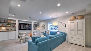 A modern living room with a large blue sectional sofa, a striped armchair, and a white cabinet with baskets on top. - Vibrant Chic Home ~ 20 Mi to Salt Lake City! (Draper)