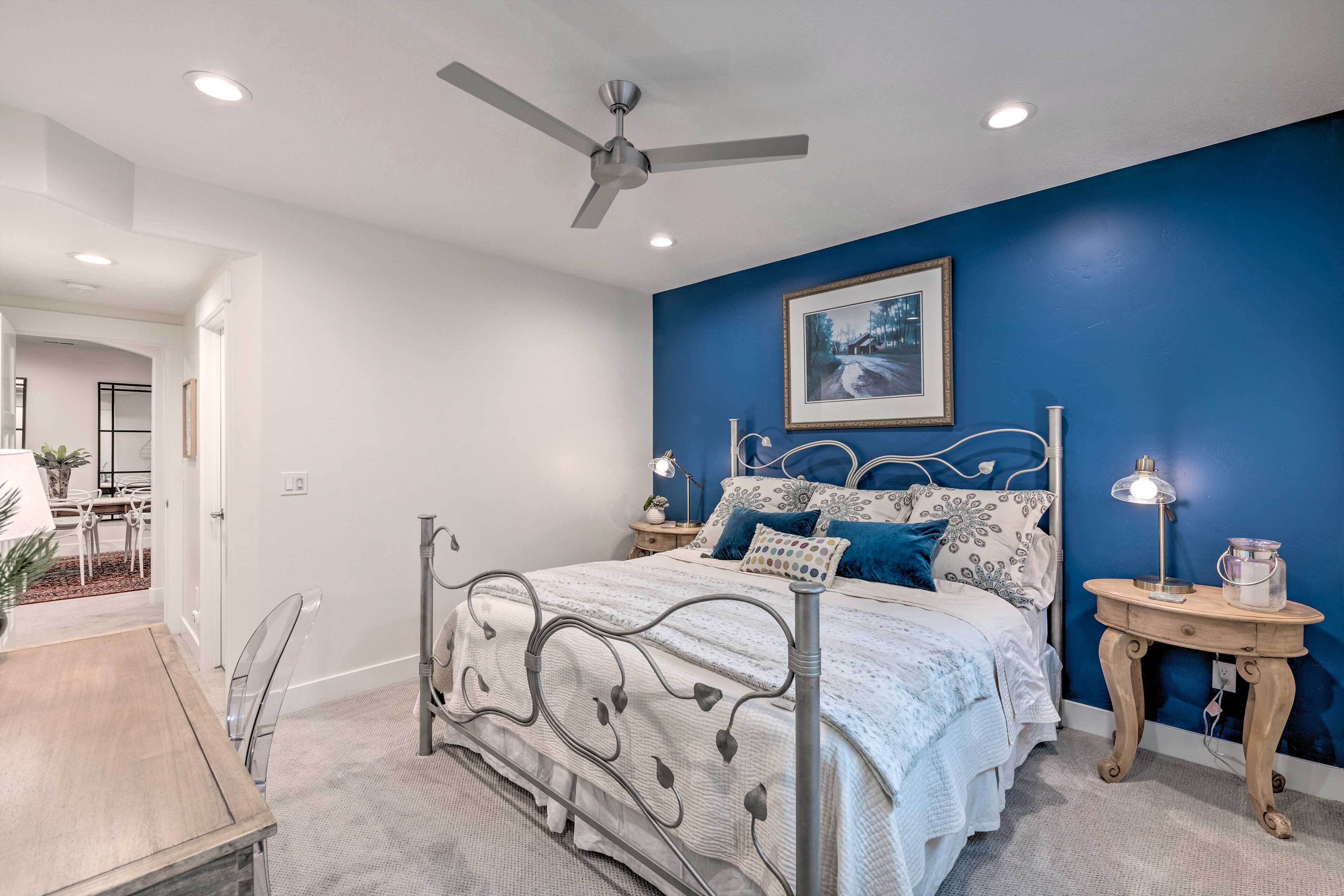 A bedroom with a bed, a ceiling fan, a bedside table with a lamp, and a framed picture on the wall.