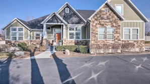 A two-story house with a stone facade, a front porch, and a driveway. - Vibrant Chic Home ~ 20 Mi to Salt Lake City! (Draper)