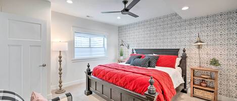 Un dormitorio con cama, ventilador de techo, mesita de noche, lámpara y pared con diseño.