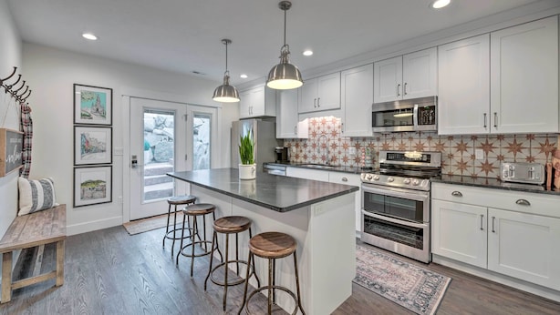 A modern kitchen with white cabinets, stainless steel appliances, and a central island with stools. - Vibrant Chic Home ~ 20 Mi to Salt Lake City! (Draper)