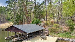 A wooden dock extending into a lake, with a covered seating area and a small building nearby. - Spacious Waterfront Hyco Lake Retreat w/ Dock! (Leasburg)