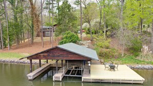 A wooden dock extending into a lake, with a covered seating area and a building in the background. - Spacious Waterfront Hyco Lake Retreat w/ Dock! (Leasburg)