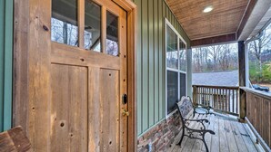 A wooden door with a glass panel, a bench, and a wooden deck with a railing. - Sevierville Cabin w/ Lake Views & Wraparound Porch (Sevierville)