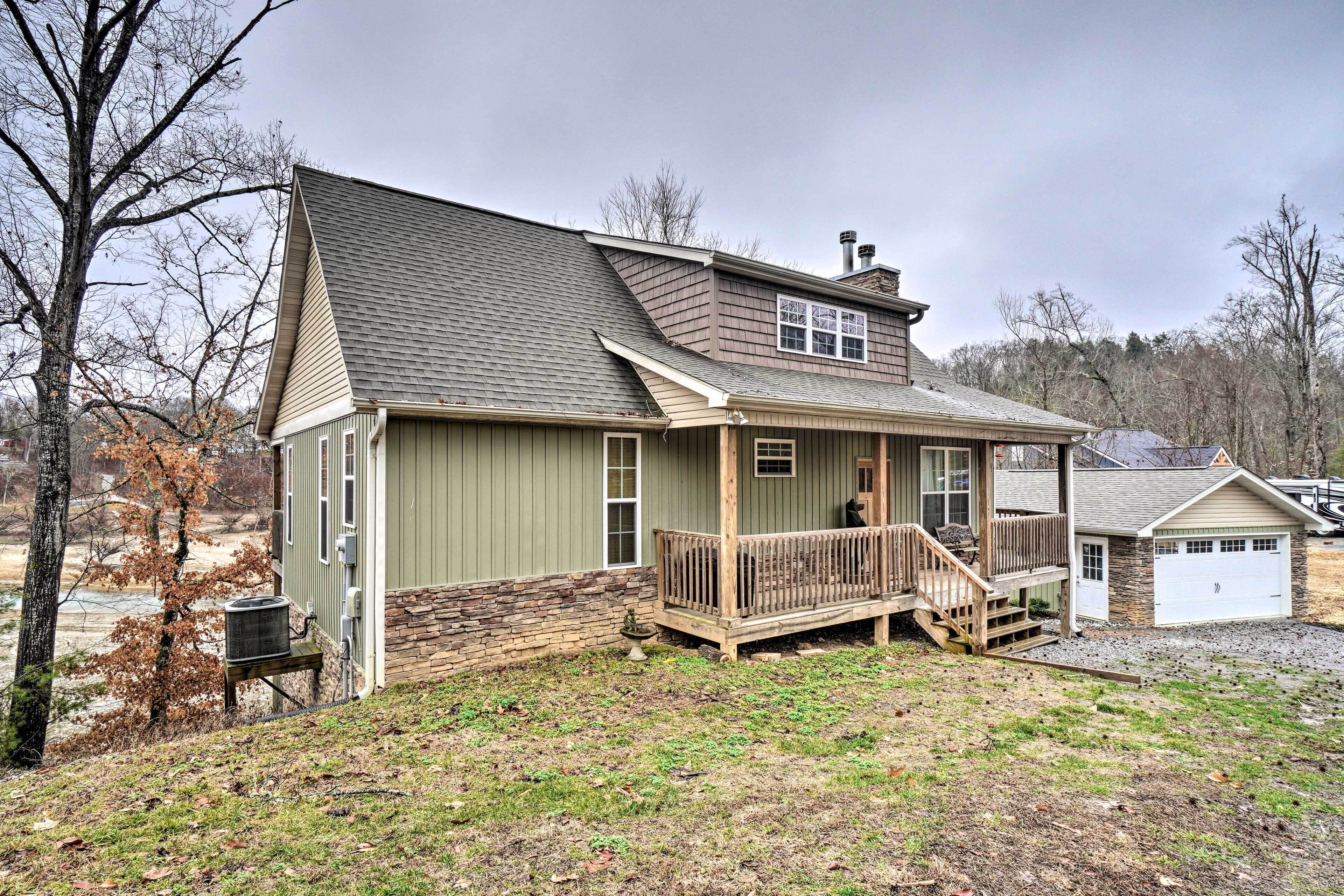 A two-story house with a front porch, a stone foundation, and a garage.