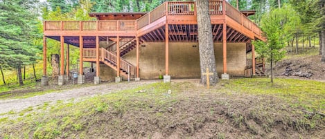 A wooden cabin with a balcony and staircase, surrounded by trees.