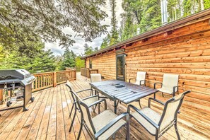 A wooden cabin with a deck, a barbecue grill, and a table with chairs. - Updated Ruidoso Cabin w/ Spacious Deck & View (Ruidoso)