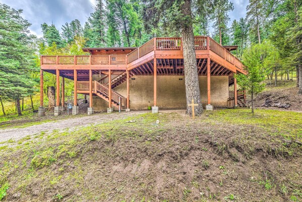 A wooden cabin with a balcony and staircase, surrounded by trees. - Updated Ruidoso Cabin w/ Spacious Deck & View (Ruidoso)