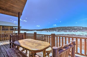 Terraza de madera con mesa y sillas con vista a un paisaje nevado.