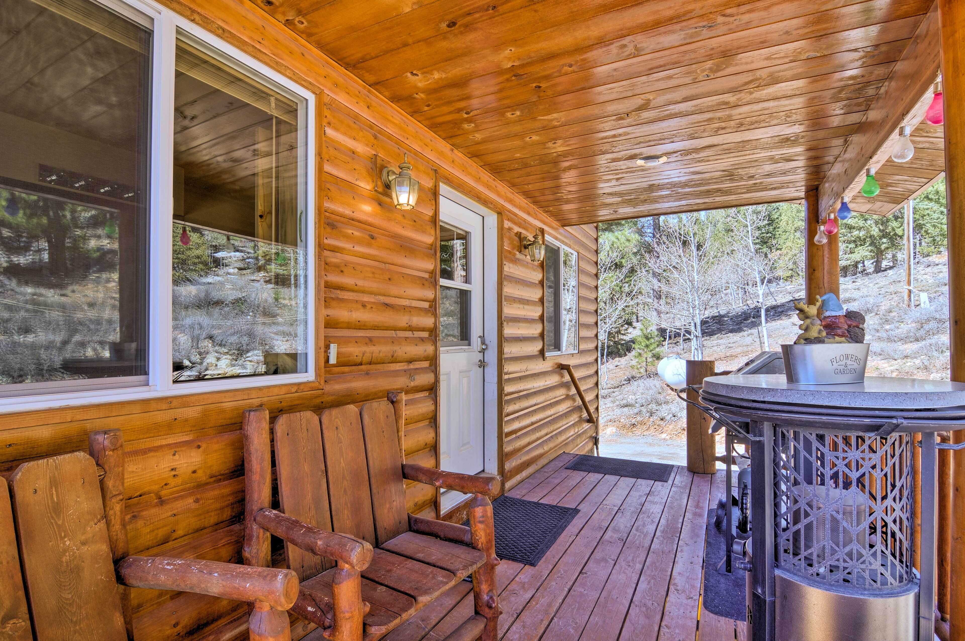 A wooden cabin with a porch, a bench, a hot tub, and a door leading outside.