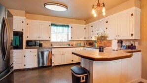 A modern kitchen with white cabinetry, stainless steel appliances, and a central island. - The Village Home w/ Pool, 12 Mi to Okc! (Oklahoma City)