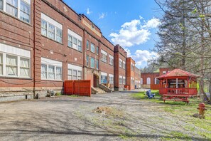 A brick building with multiple windows, a red fire hydrant, and a small red structure.