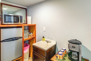 Une petite cuisine équipée comprenant un réfrigérateur, un four à micro-ondes, un évier et une machine à café.