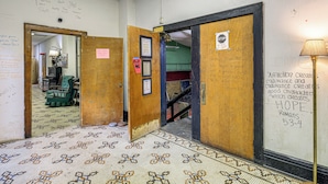 Un pasillo con baldosas de diseño, puertas de madera y una pared con varias inscripciones y una lámpara.