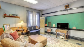 Una sala de estar con sofá, reposapiés y televisor.