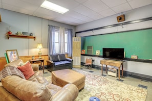 A living room with a sofa, ottoman, and a television. - Direct Warrior Trail Access! Ultimate ATV Getaway (Gary)