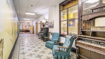 A hallway with patterned flooring, a piano, and two armchairs.