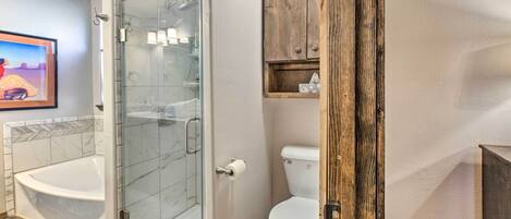 A modern bathroom with a glass-enclosed shower, a white toilet, and a wooden cabinet.